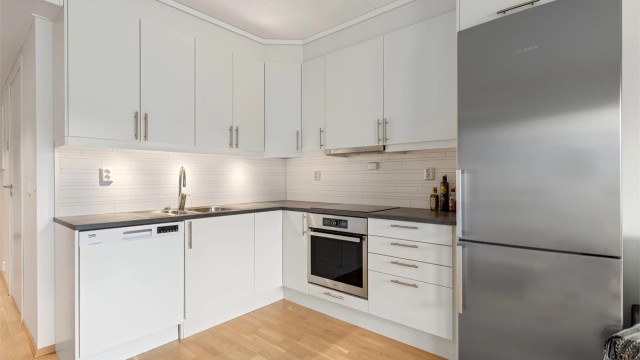 Moderne kjøkken med takhøye skap. Komfyrvakt er montert. Avtrekk over kokeplaten går ut.