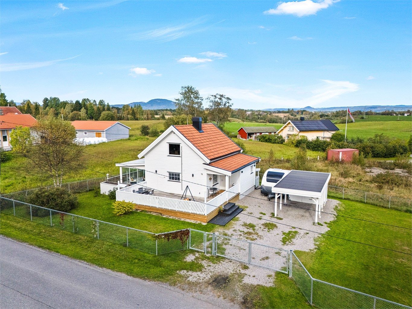 Tomten er solrik, med store inngjerdede plenarealer og frittstående bod med carport på gruslagt gårdsplass.