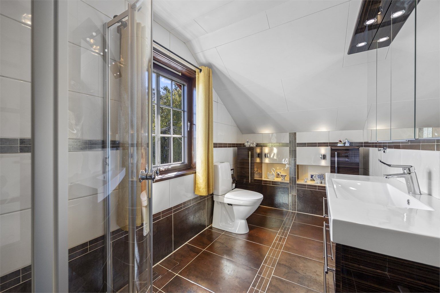 Badet er innredet med vegghengt servantinnredning og gulvstående toalett.