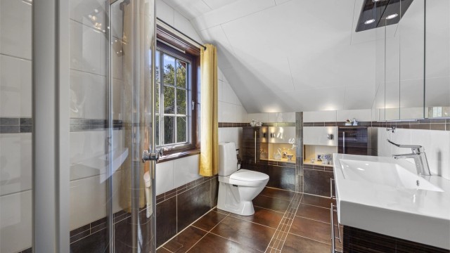 Badet er innredet med vegghengt servantinnredning og gulvstående toalett.