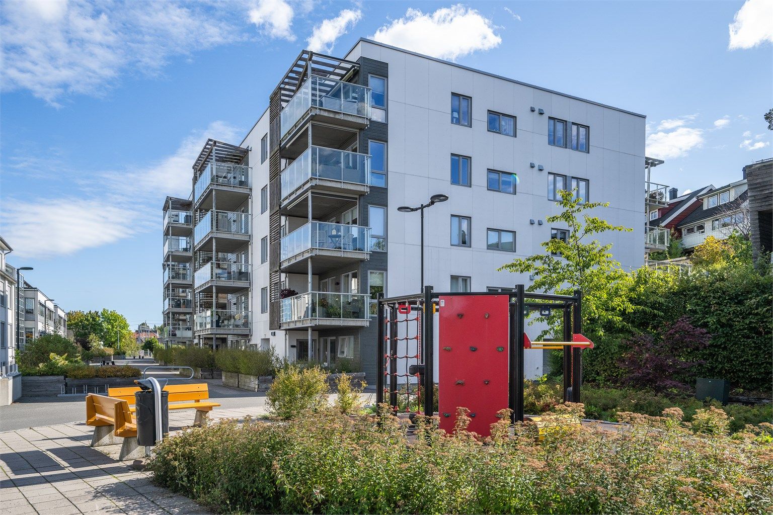 Skjermet gårdsrom med sittebenker og lekeapparater for beboerne.