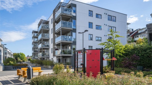 Skjermet gårdsrom med sittebenker og lekeapparater for beboerne.