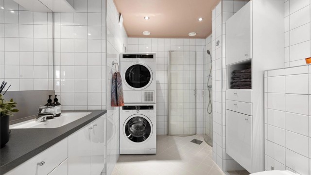 Flislagt bad har innredning med hvite glatte fronter. Det er også veggskap med god oppbevaringsplass. Dusjhjørne med foldbare dører og dusjarmatur. Opplegg for vaskemaskin og tørketrommel