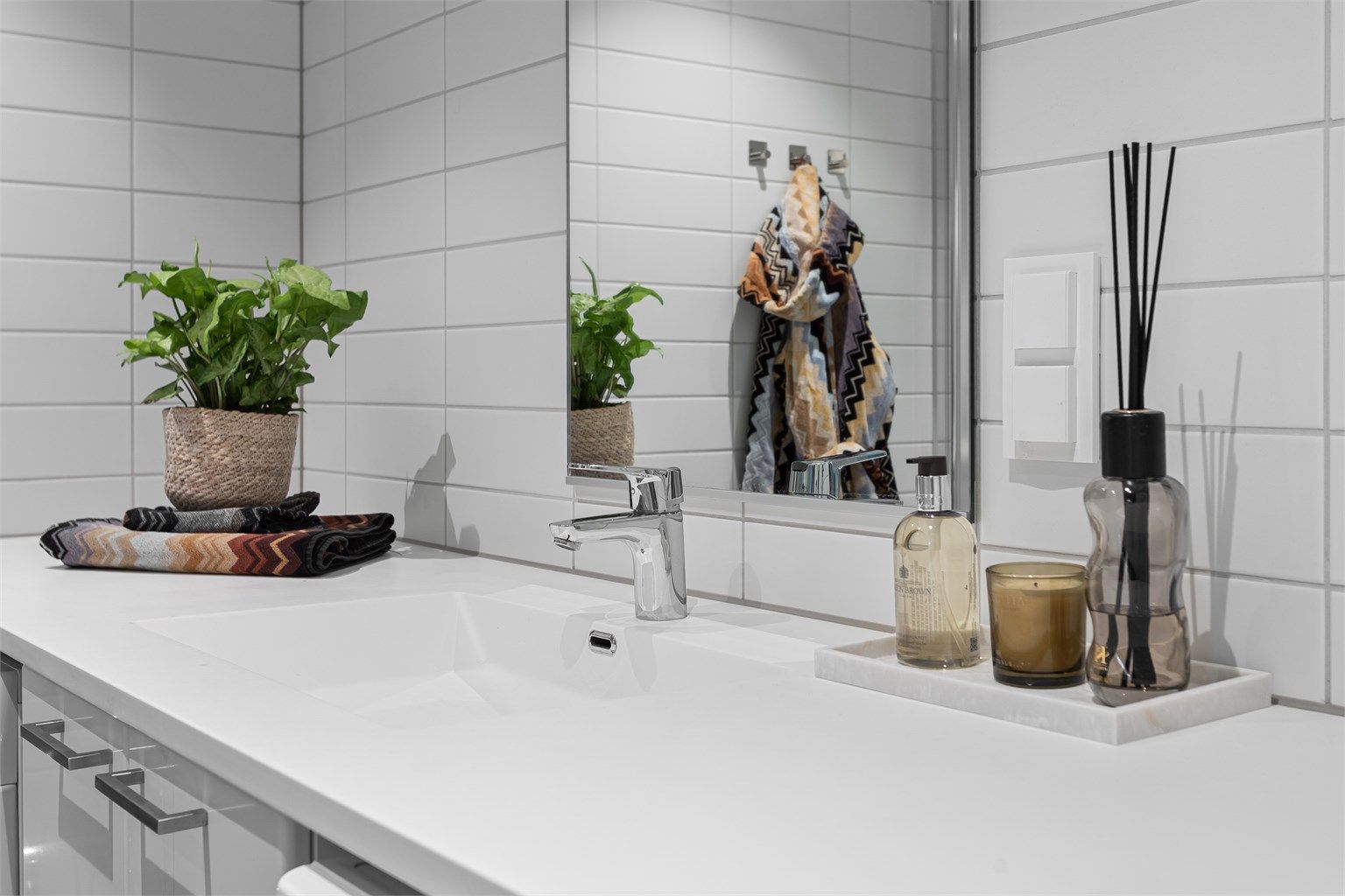 Rommet har god plass til både vaskemaskin og tørketrommel, og er innredet med en heldekkende servant med tilhørende underskap og servantplate som gir rikelig med benkeplass. 