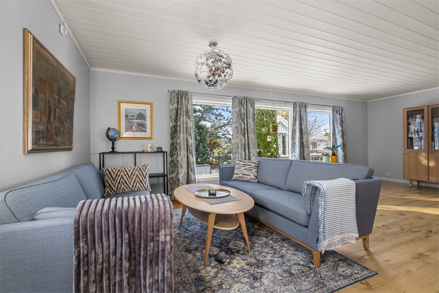 Romslig stue på 27 kvm med gode møbleringsmuligheter og store vinduer som slipper inn mye naturlig lys.