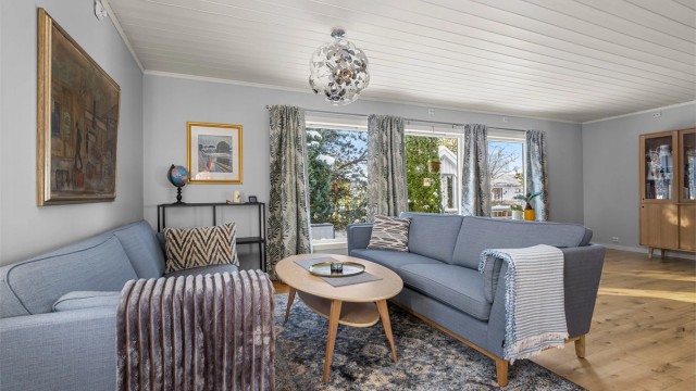 Romslig stue på 27 kvm med gode møbleringsmuligheter og store vinduer som slipper inn mye naturlig lys.