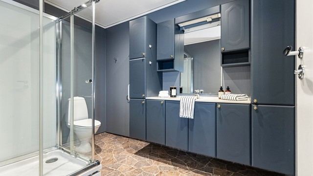 Badet er utstyrt med dusjkabinett, toalett og servantinnredning med god skapplass.
