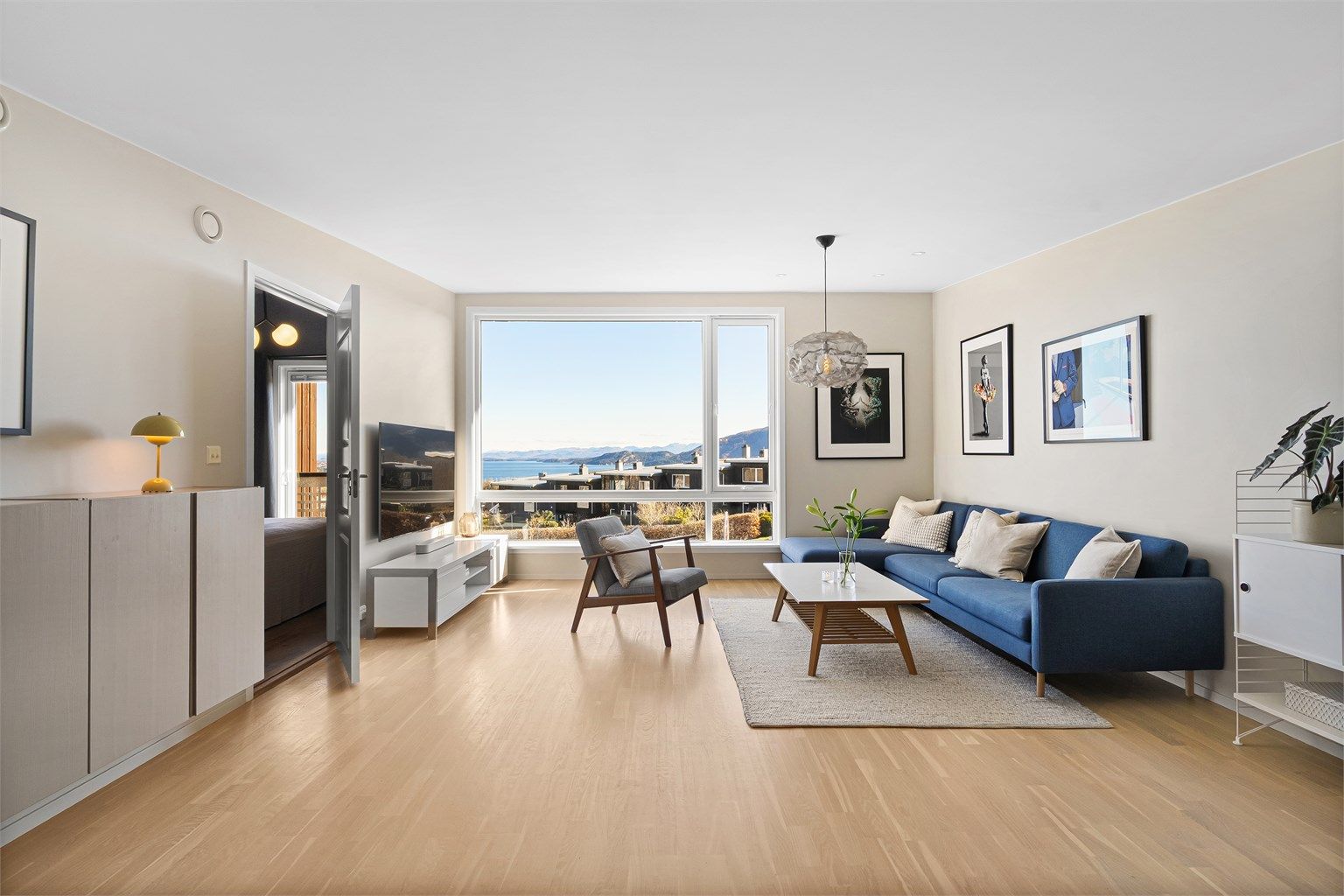 Lys stue med ekstra takhøyde, store vinduer og flott sjøutsikt.