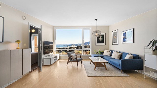 Lys stue med ekstra takhøyde, store vinduer og flott sjøutsikt.