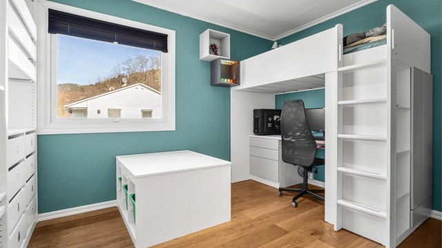 Det andre rommet i 1. etasje har en innebygget åpen garderobeløsning med hyller, skuffer og klesskinner.