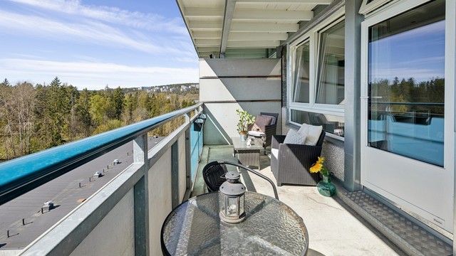 Utsikten fra balkongen strekker seg mot skogkanten, og gir en følelse av ro og natur.