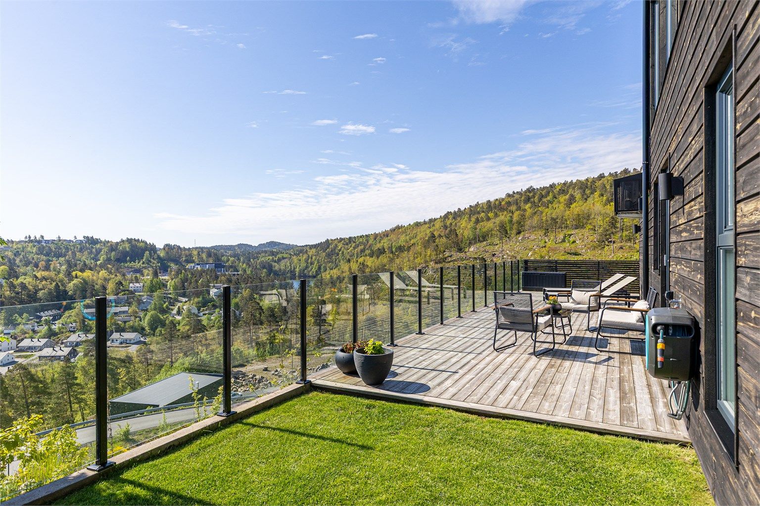 Flott, opparbeidet uteplass med glassrekkverk, terrasse, plen og asfaltert tun.