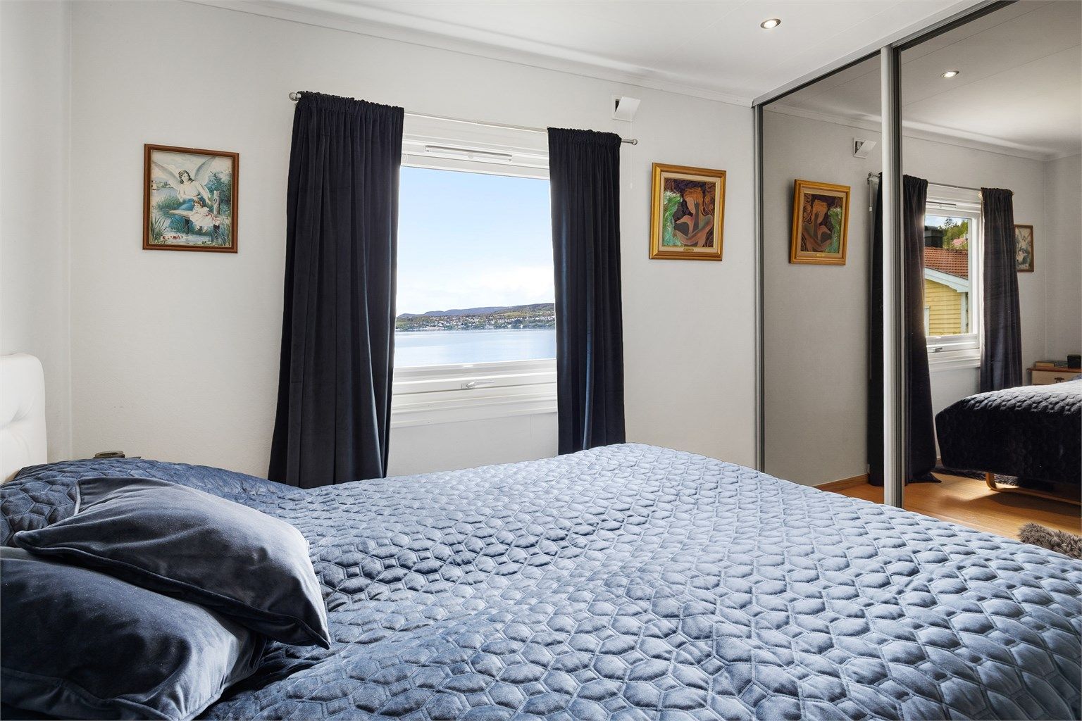 Hovedsoverom med skyvedørsgarderobe og utsikt mot fjorden.
