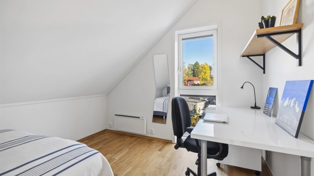 Boligens tredje soverom er lyst og trivelig, med store vinduer som gir rikelig med naturlig lys. En egen nisje gir god plass til en stor seng og bidrar til en lun og harmonisk atmosfære.