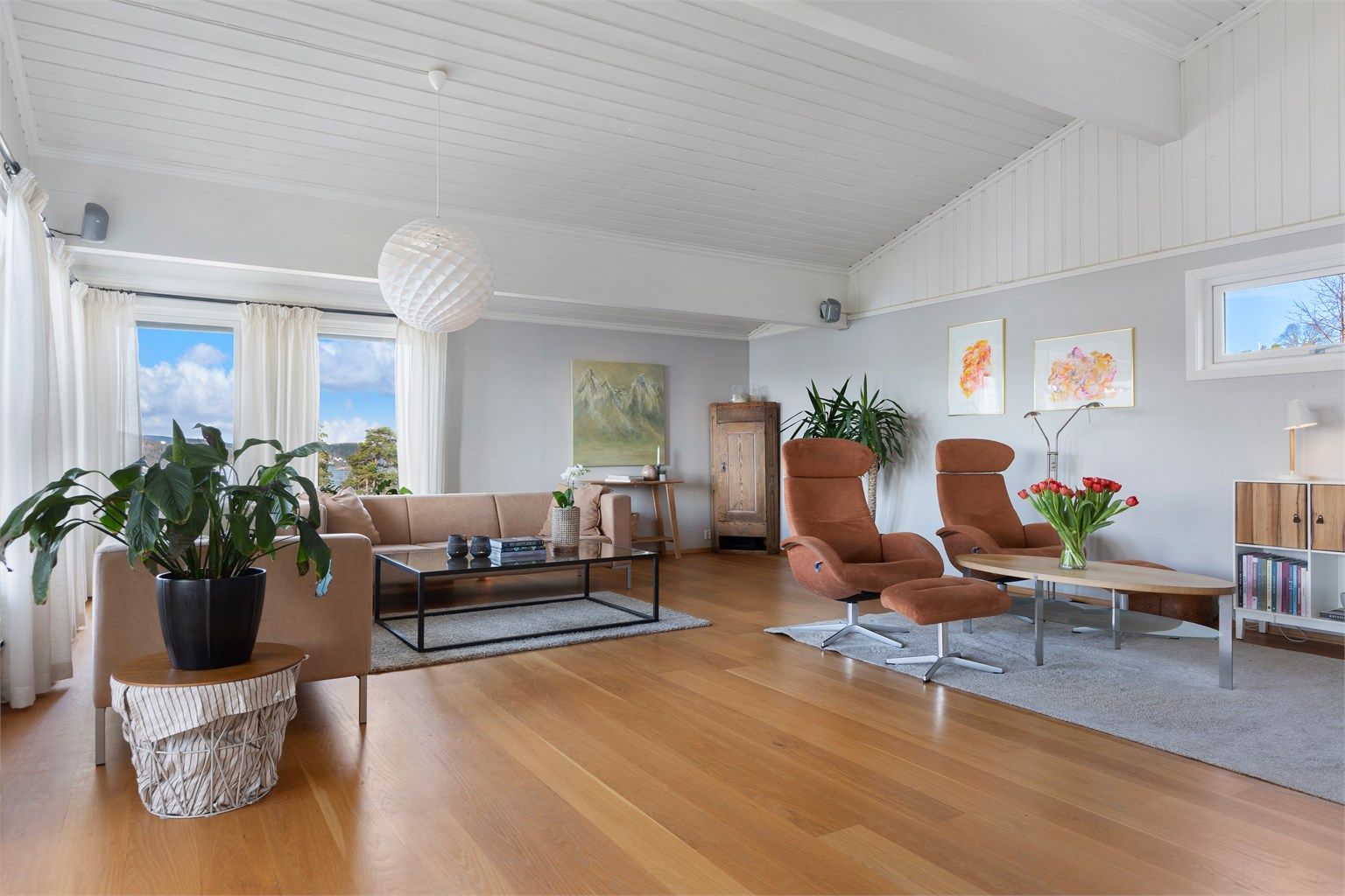 Den romslige stuen har parkettgulv og store vindusflater som slipper inn rikelig med lys.