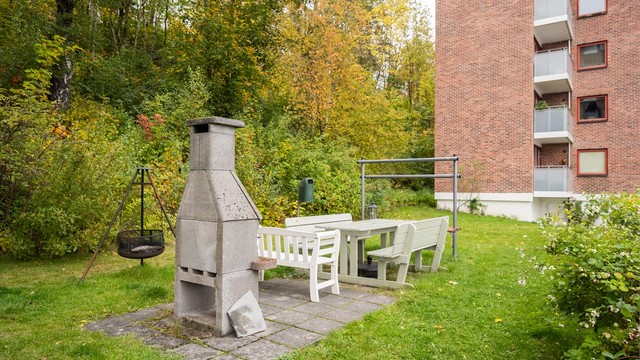 Grønt fellesområde med murt utepeis og benker for beboerne.