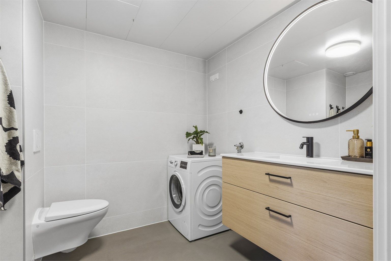Badet består av vegghengt servantinnredning, speil med lys, dusjnisje med dører, vegghengt dusjarmatur og vegghengt toalett