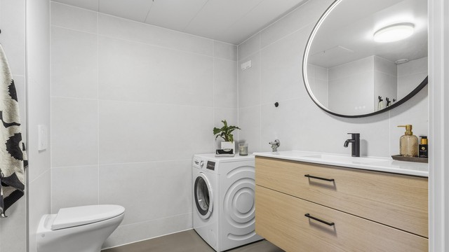 Badet består av vegghengt servantinnredning, speil med lys, dusjnisje med dører, vegghengt dusjarmatur og vegghengt toalett