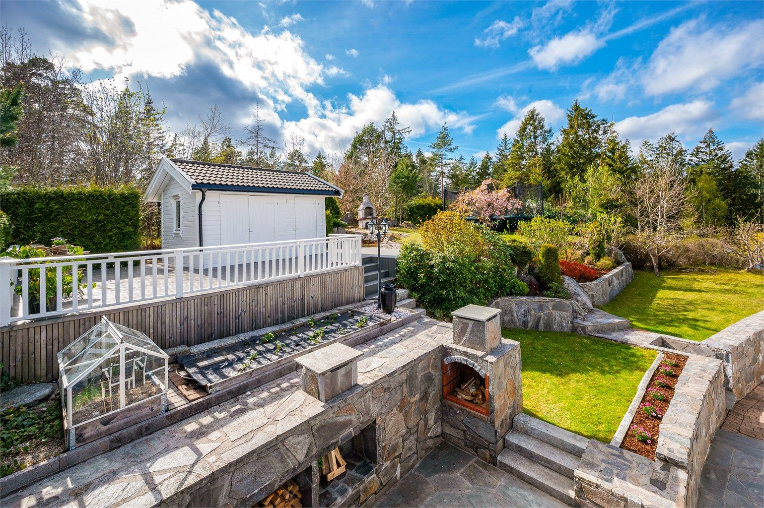 Flere fine og solrike uteplasser med utepeis og frodig hage. Frittliggende bod på den ene terrassen.