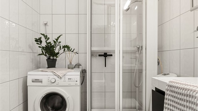 Innredet med vegghengt servantinnredning, speilskap med overlys, dusjkabinett og gulvstående toalett.