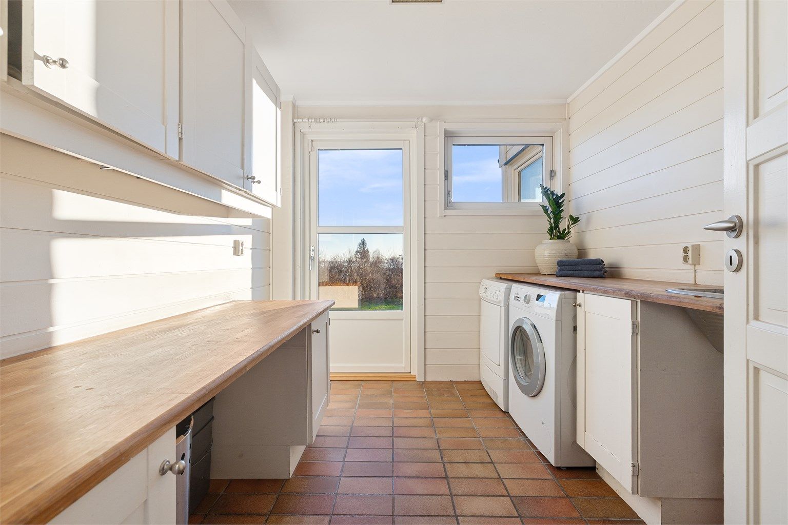 Praktisk vaskerom med direkte utgang til felles hage. Benkeskap med benkeplater i tre, overskap og utslagsvask med ett-greps armatur. Rommet har avtrekksventil i himlingen. Vaskemaskin og tørketrommel medfølger.