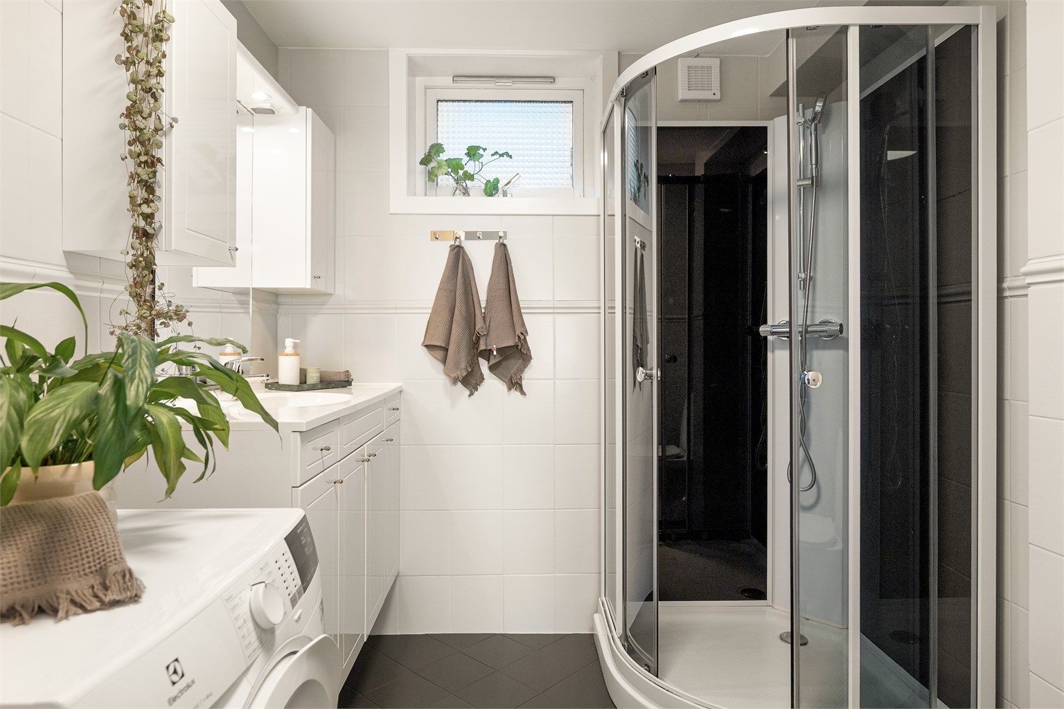 - Badet er innredet med dusjkabinett, toalett, vegghengt servant med oppbevaring og opplegg for vaskemaskin -