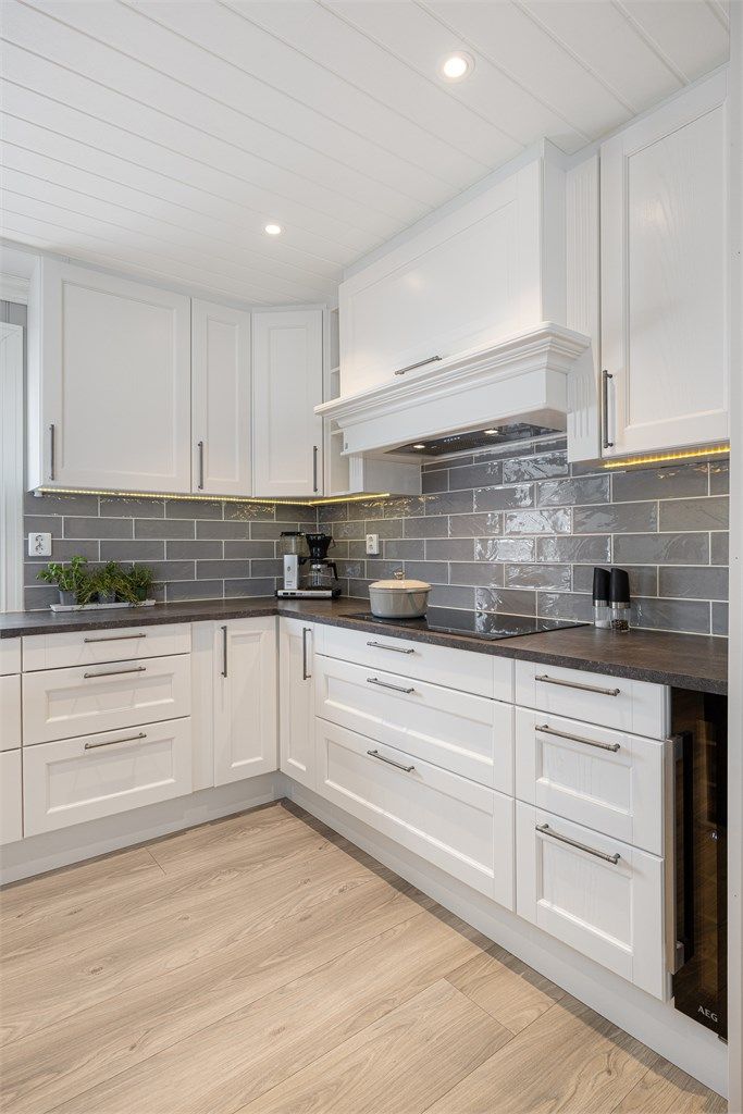 Kjøkkeninnredningen har hvite 1-speils fronter og en slitesterk benkeplate i laminat.