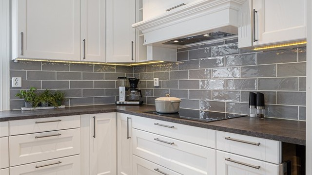 Kjøkkeninnredningen har hvite 1-speils fronter og en slitesterk benkeplate i laminat.