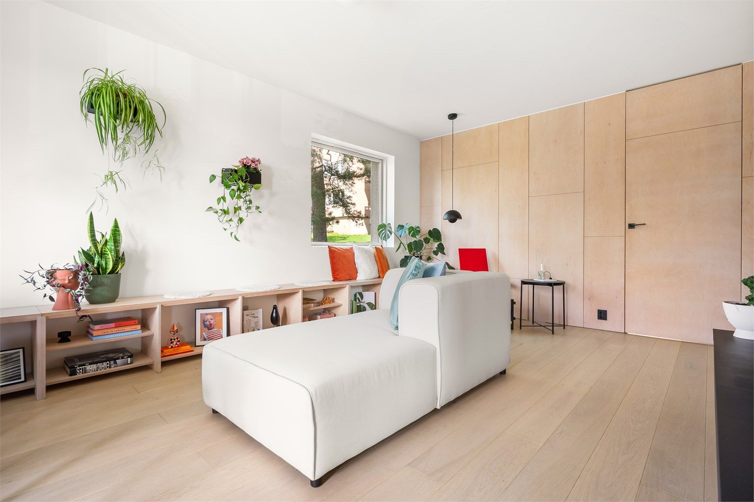 Stuen er romslig og fleksibel. Den er naturlig delt inn i tre soner: en hyggelig lesekrok ved vinduet, en sofagruppe med sjeselong som kan nytes fra to vinkler mot peisen, og en spiseplass.