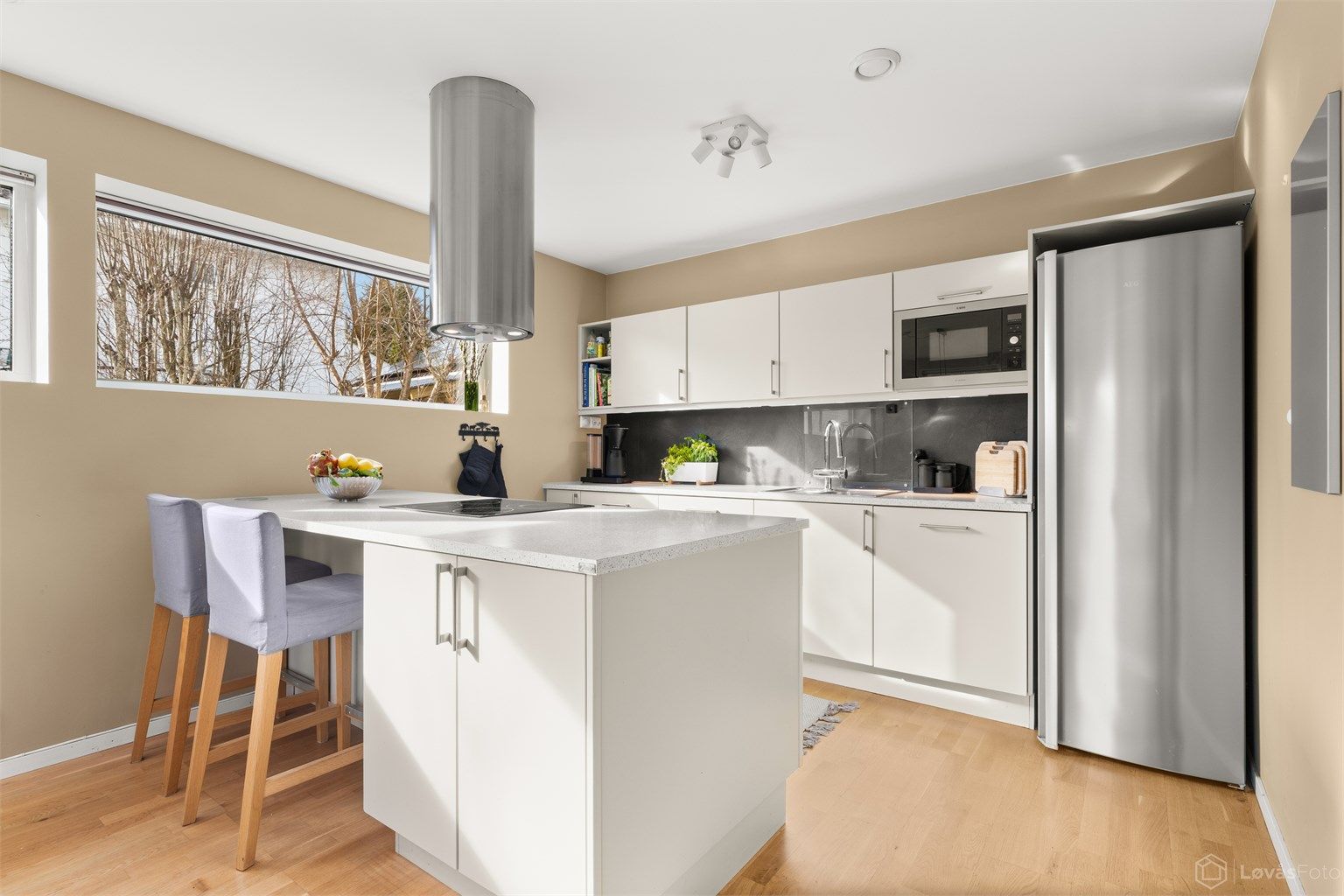 Kjøkkeninnredningen har glatte fronter og en solid laminert benkeplate.