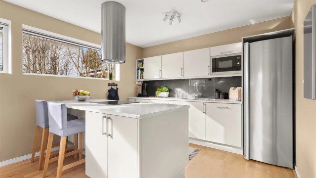 Kjøkkeninnredningen har glatte fronter og en solid laminert benkeplate.