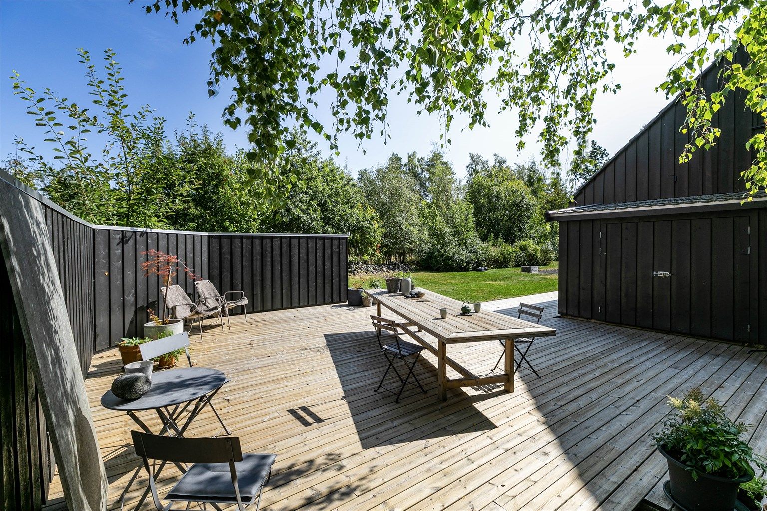 Bakhagens skjermede terrasse er som skap for måltider og sammenkomster under åpen himmel.