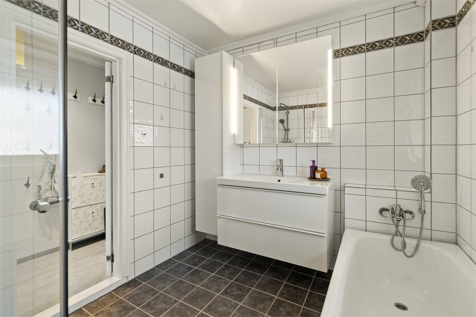 Servant i innredning, speilskap, badekar og dusjnisje.