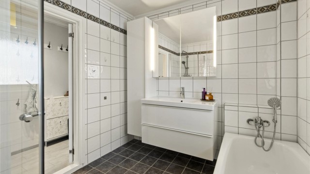 Servant i innredning, speilskap, badekar og dusjnisje.