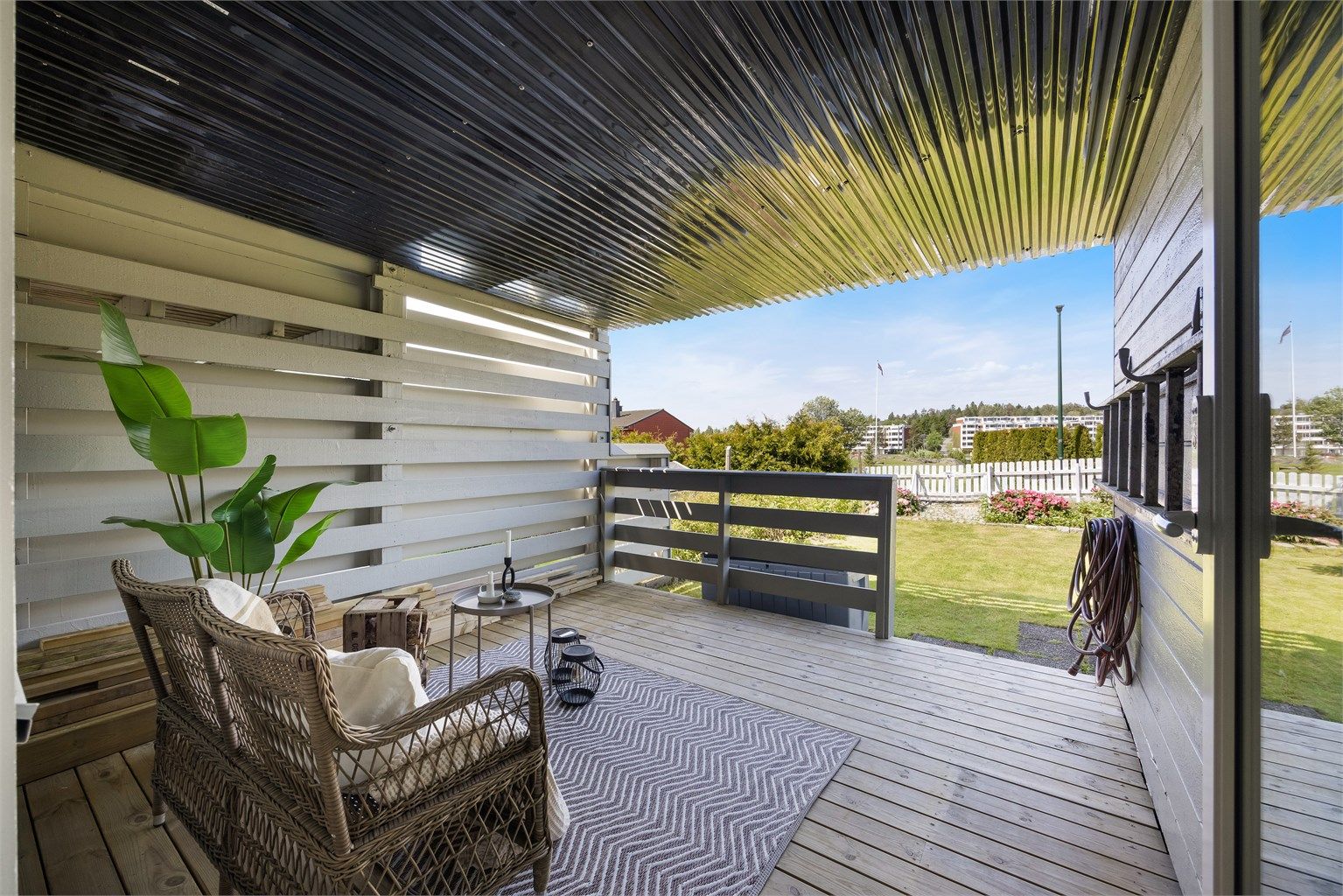 Lun og innbydende terrasse med takoverbygg som gir gode møbleringsmuligheter og en naturlig forlengelse av boligens oppholdsarealer.