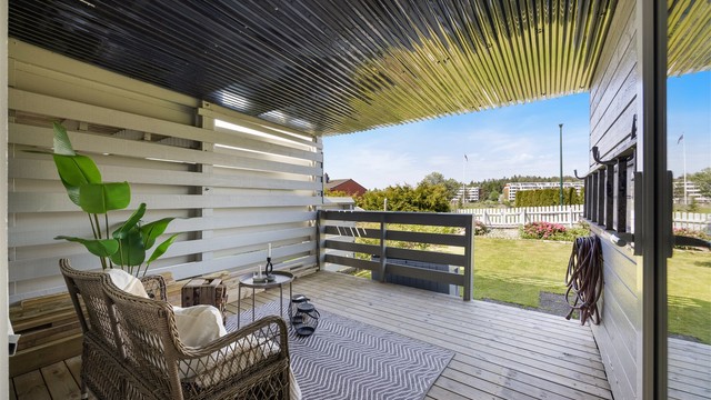 Lun og innbydende terrasse med takoverbygg som gir gode møbleringsmuligheter og en naturlig forlengelse av boligens oppholdsarealer.
