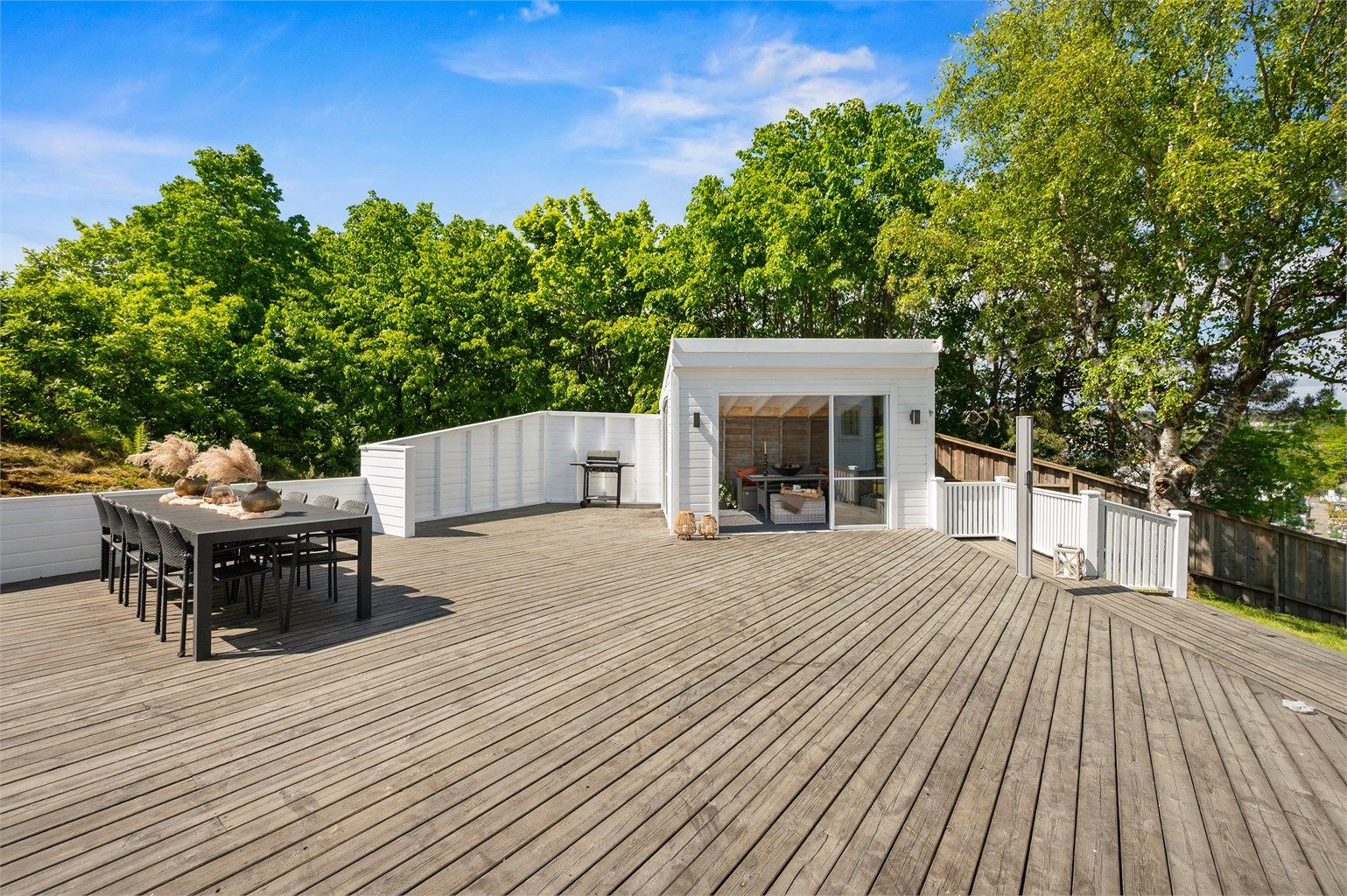 God plass for flere sittegrupper, solsenger og spisebord. Utestue og levegg som gir ekstra skjerming.