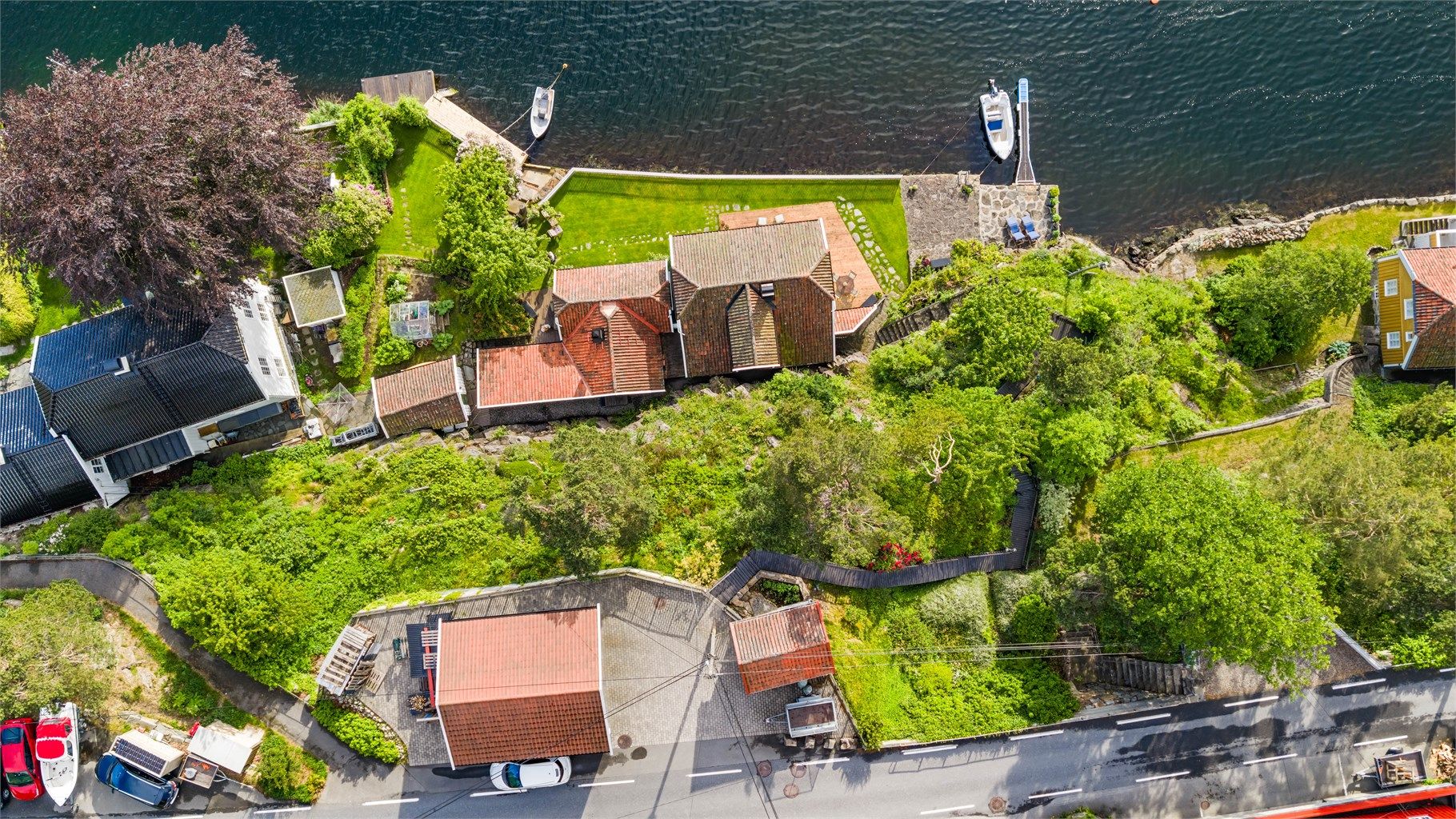 Oversiktsbilde som viser eiendommens plassering i terrenget, fra vei til sjø.
