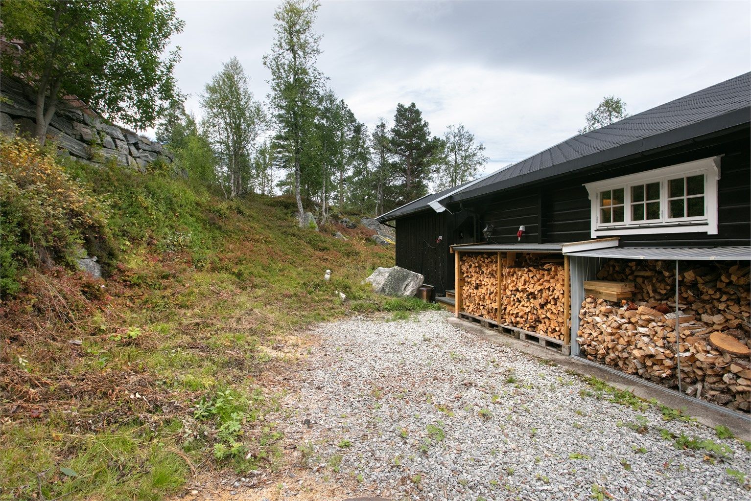 Gruset og singelt rundt hytten som forøvrig har naturtomt. God plass til ved på eiendommen