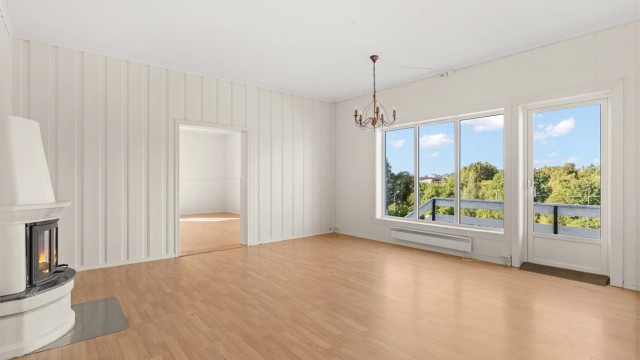Lys stue med stemningsfull peisovn og direkte utgang til terrassen.
Foto: Løvås Foto