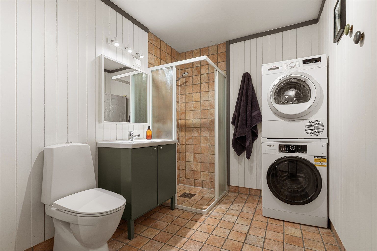 Romslig bad med servant innredning, dusjhjørne og opplegg for vaskemaskin/tørketrommel