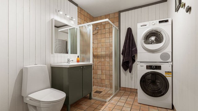 Romslig bad med servant innredning, dusjhjørne og opplegg for vaskemaskin/tørketrommel