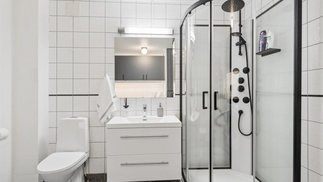 Badet har flislagt gulv med gulvvarme, fliser på veggene og innredning med servant, speil og høyskap.
