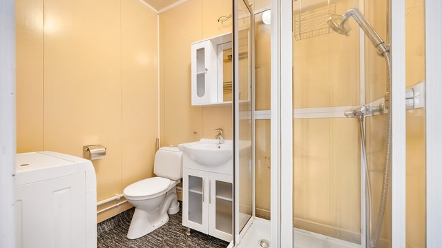 Badet er utstyrt med dusjkabinett, toalett og servantinnredning.