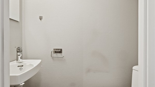 Leiligheten har et separat toalettrom med vegghengt servant og flislagt gulv.