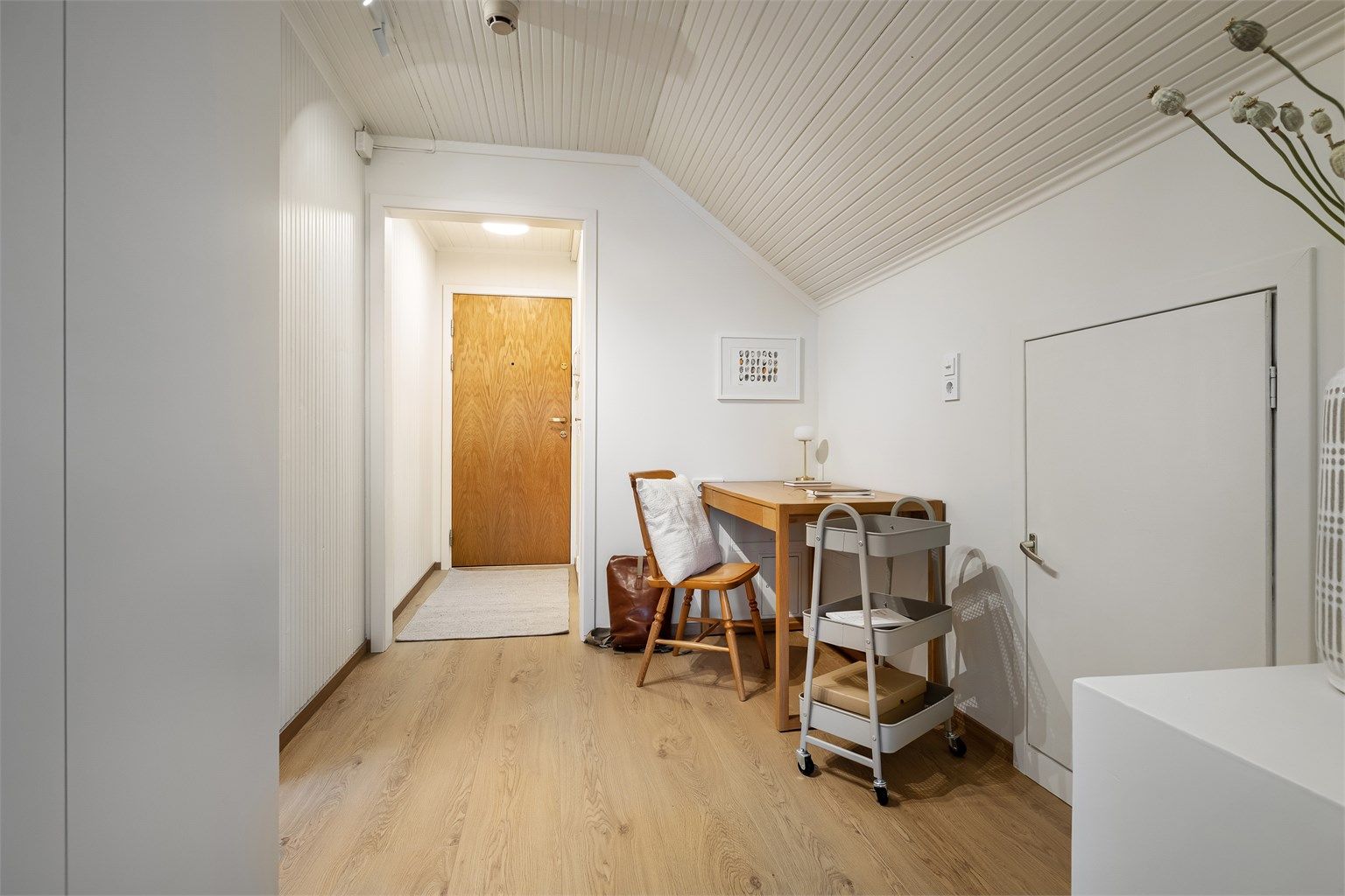 Lys og romslig gang med malte vegg- og himlingsflater og laminat på gulv