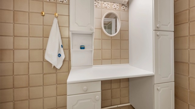 Badet er innredet med vegghengt servantinnredning, speil med overlys, vegghengt skap, dusjkabinett i hjørne samt et veggehngt baderomsmøbel med ekstra oppbevaringsplass.
