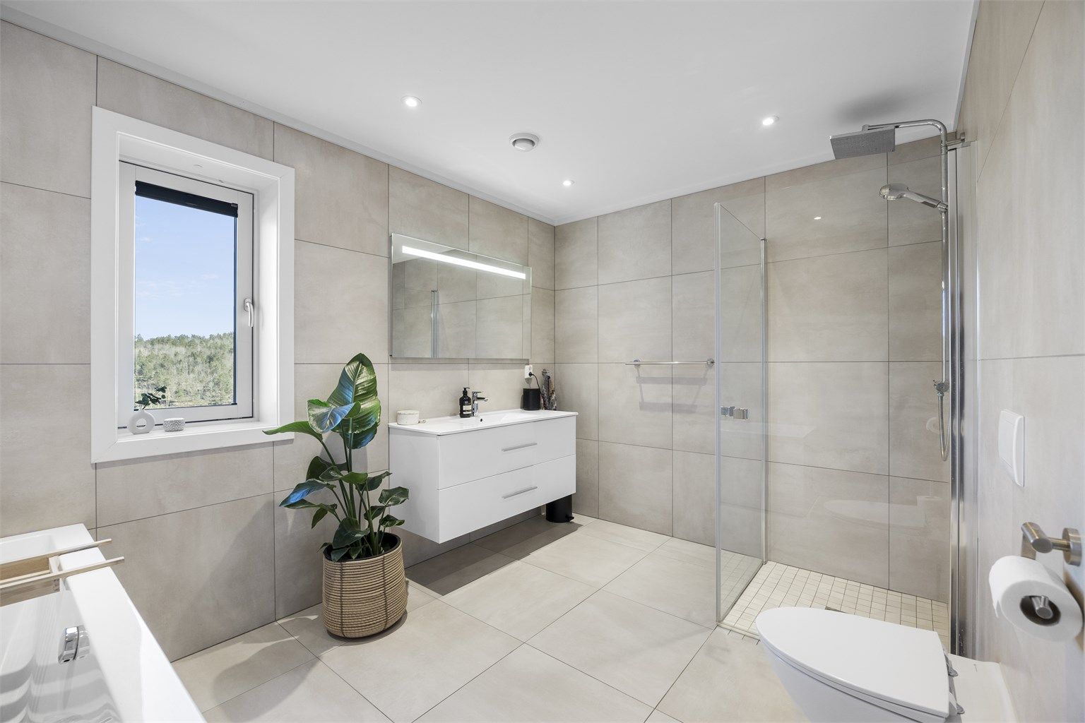 I tillegg til badekar har badet et separat dusjhjørne med glassdører og regnfallsdusj.