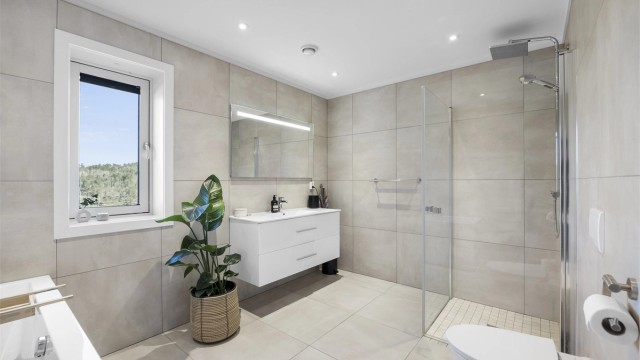 I tillegg til badekar har badet et separat dusjhjørne med glassdører og regnfallsdusj.