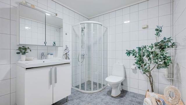 Helfliset romslig bad fra ukjent årstall som er innredet med baderomsmøbler, speilskap, dusjhjørne med dører og gulvstående toalett. Her er også opplegg for vaskemaskin.